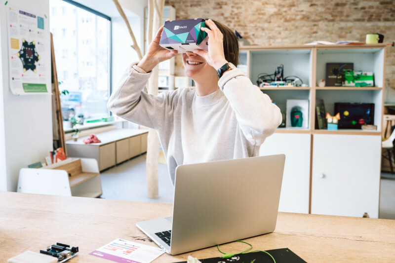 E! Eine Frau h&auml;lt sich eine VR-Brille vor die Augen.