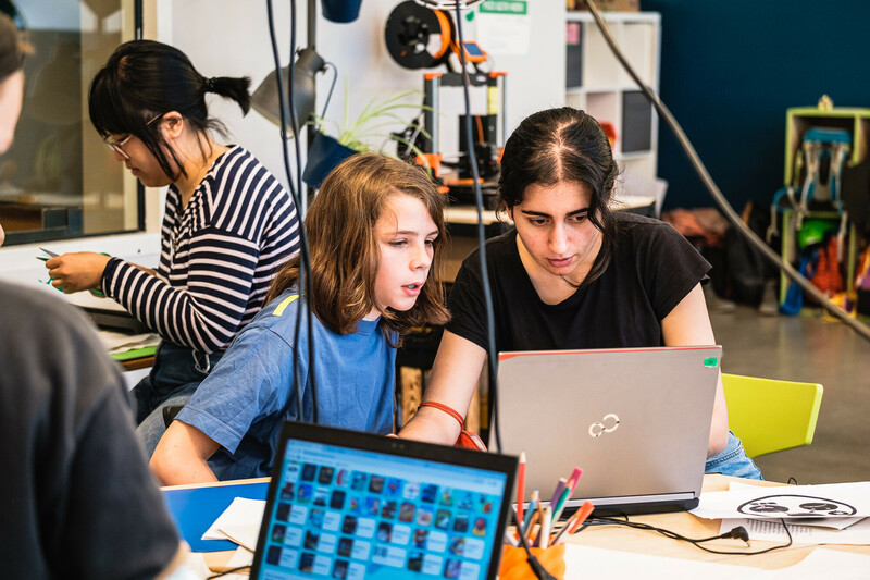 E! Eine Mentorin t&uuml;ftelt mit einem Jungen gemeinsam an einem Laptop.