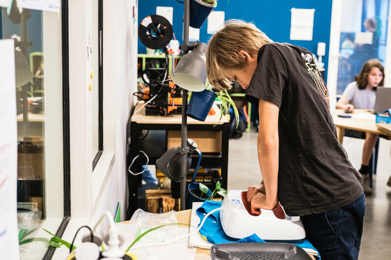 E! Ein Junge presst einen Druck auf ein T-Shirt.