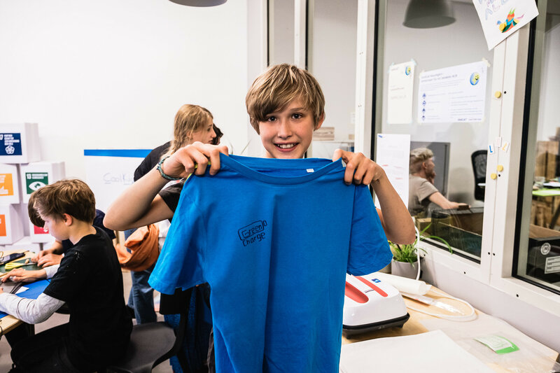 Ein Kind hält ein selbstgedrucktes T-Shirt hoch