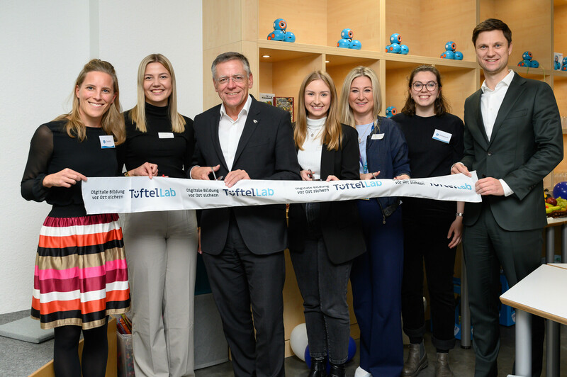 7 Personen stehen hinter einer Schleife, die feierlich durchgeschnitten wird.